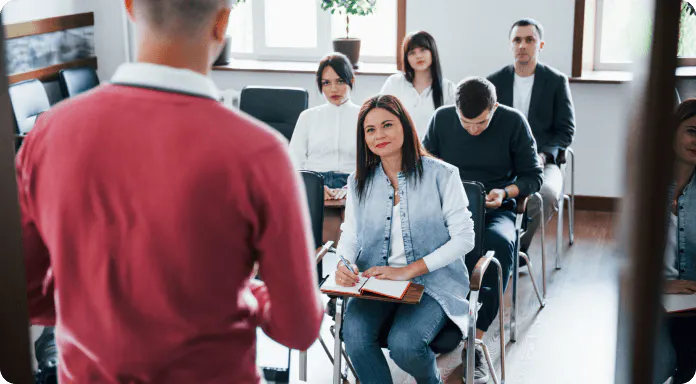 Homem dando aula enquanto pessoas o ouvem com atenção