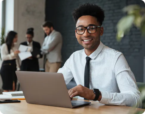 Homem sentado sorrindo mexendo no computador